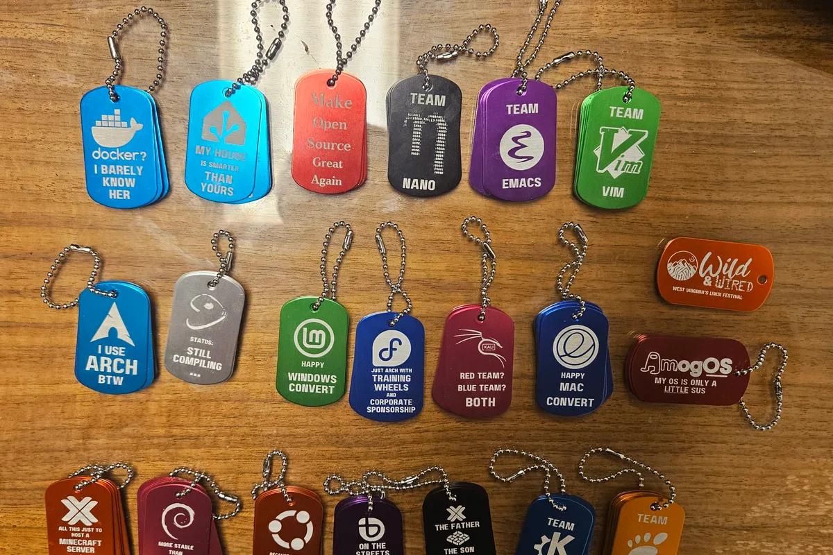 Rows of coloured metal dog tags on a wooden table, each engraved with a Linux distribution logo or a joke such as I use Arch by the way